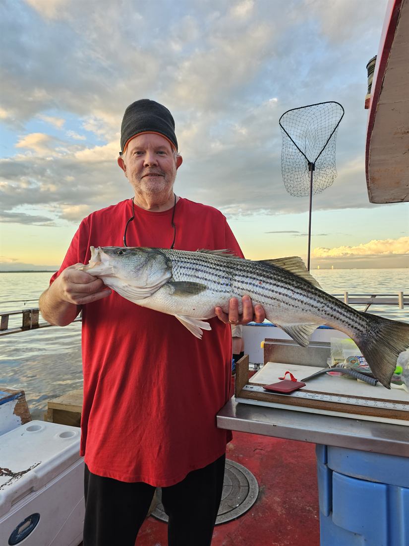 Striped bass held up at sunset
